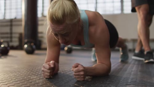 Close up of fit caucasian woman performing plank exercise at the gym