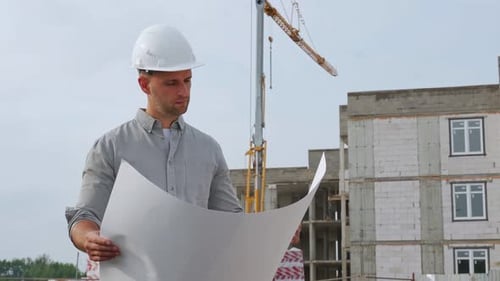Architect Holding Blueprint Smiling at Camera at Construction Site
