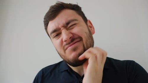 Retrato de un joven con estilo se rasca la barba y grita de dolor