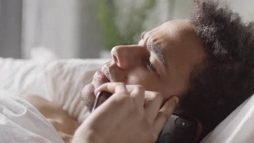 Young Adult Talking on Phone in Bed