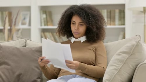 Woman Reading Documents at Home on Sofa