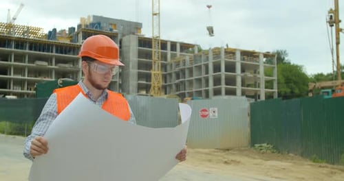 Architect Man Walking on the Construction Site and Analyzing Scheme Project Plan. Young Architect or