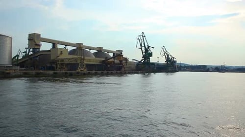 Boot fährt auf dem Seeweg, nähert sich dem Kai mit riesigen Lagerhäusern und Kränen am Hafen