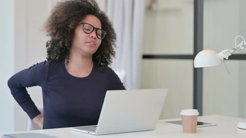 Young Woman Massaging Lower Back at Computer
