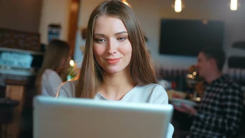 Young Happy Woman Using Tablet Computer in a Cafe