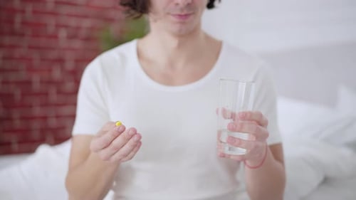 Young Adult Holding Pill and Glass of Water