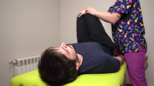 physiotherapist mobilizing patient with both legs