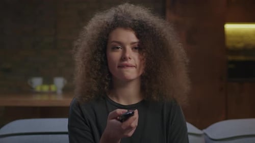 Young Woman Smiles Holding TV Remote