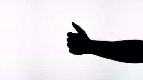 Silhouetted Hand Gives a Thumbs Up on Gray