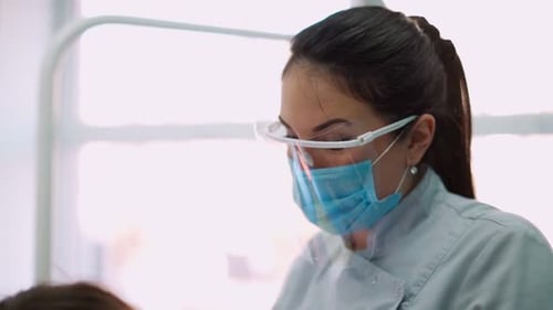 Woman Doctors in Protective Masks in Dental Clinic Serve Patient