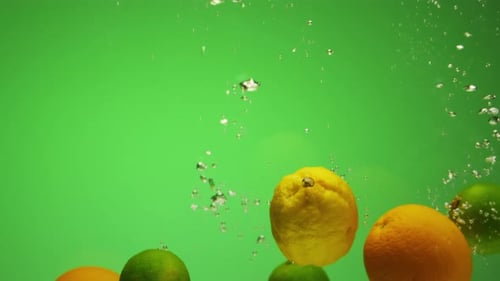 Citrus Fruits Falling in Water with Bubbles Green Background in Slow Motion Orange Lime Lemon