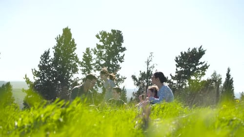 Una familia con 4 niños haciendo un picnic al aire libre en una colina verde bajo el sol