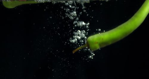 Green Chili Pepper Falling Into the Water with Air Bubbles.
