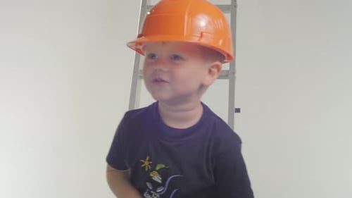 Child in Hard Hat Smiling with Hammer
