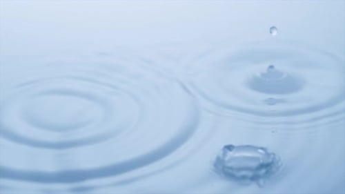 Water Droplets Creating Ripples on Blue Surface