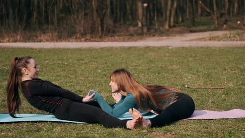 Two Women Stretch Together in Sunny Rural Park