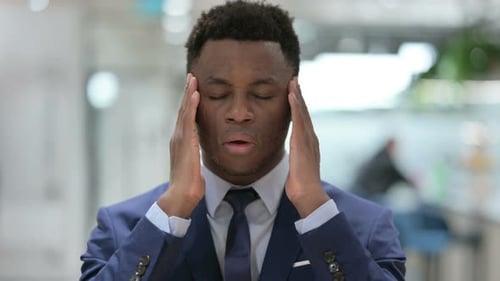 Adult Man in Suit Rubbing Temples in Office