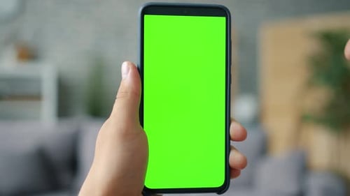 Close-up of Male Hand Holding Chroma Key Green Screen Smartphone in Apartment