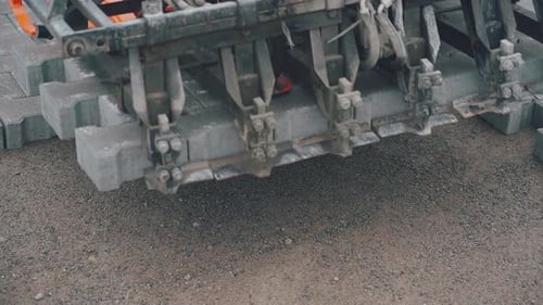 The machine installs the grey pavement.Close-up video.