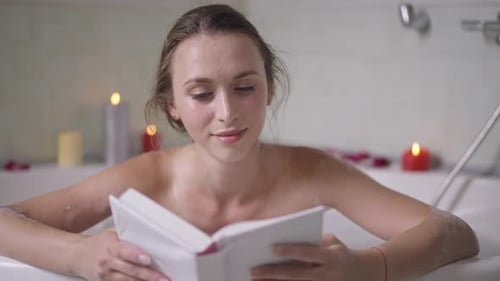 Woman Reading Book in Candlelit Bubble Bath