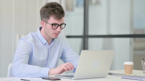 Young Adult Massaging Stiff Neck at Office Desk