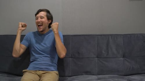 Man Expressing Joyful Enthusiasm on Gray Couch