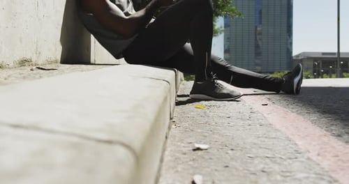 Athletic Man Resting After Workout with Phone in City