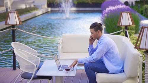 Young Adult Working Outdoors with Laptop and Phone