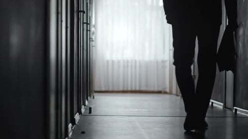 Silhouette Walking Down Ominous Lit Hallway