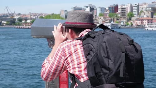 Junger Tourist schaut durch das Big Street Fernglas-Teleskop auf wunderschöne touristische Orte