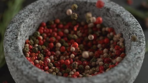 Pepper falling into a stone mortar bowl