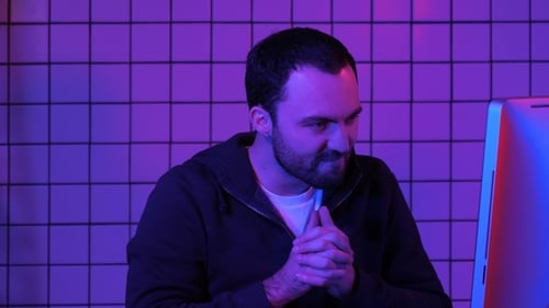 Young Adult Looks at Computer Screen in Neon Lighting