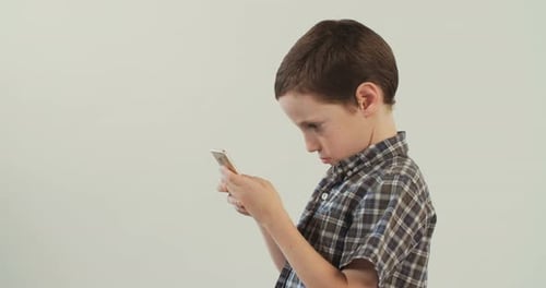 Young boy plays with a mobile phone on a white studio background