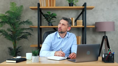 Adult Man Writing in Notebook at Desk