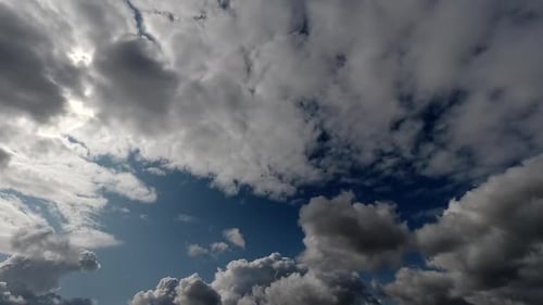 Zeitraffer: Die Sonne versteckt sich hinter flauschigen Wolken, die am Himmel fliegen.