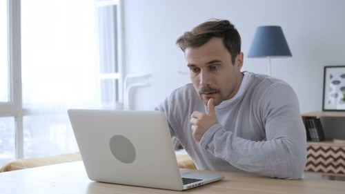 Man Working on Laptop at Table Indoors