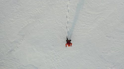 Top View a Lone Traveler with a Backpack Walks Through the Snowy Desert
