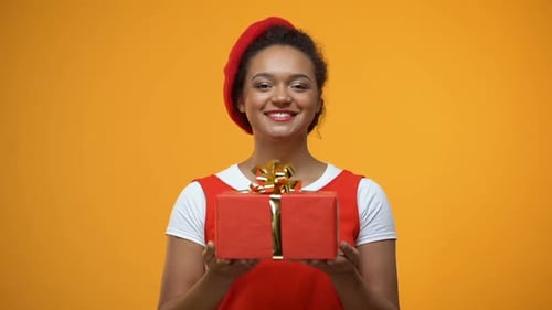 Smiling Woman Holding Out Red Gift
