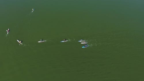 Athletes at Stand up Paddle Competition on SUP Board bypassing Buoy on Dark Green Water