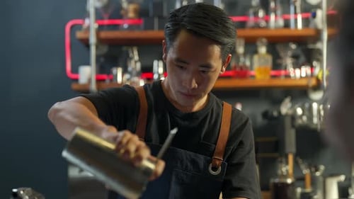 4K Asian man barista serving iced black coffee in cocktail glass to customer at coffee shop.