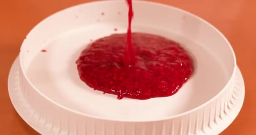 Bright Red Liquid Pours Into White Container