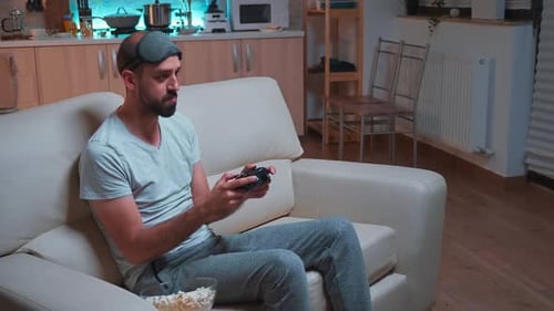 Man Plays Video Game on Couch at Home