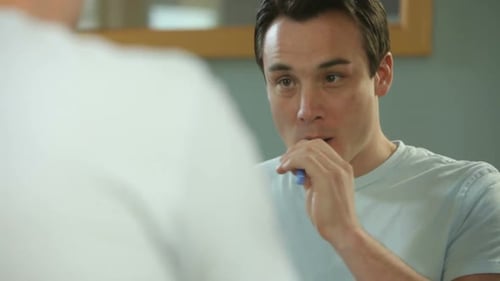Man in bathroom brushing teeth