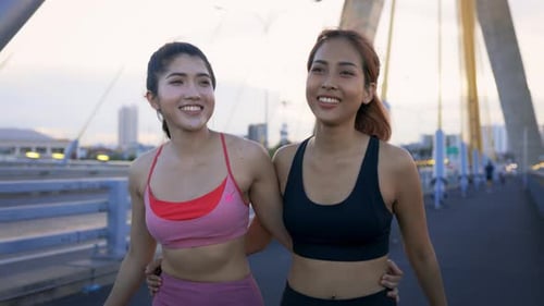 Young Female Athletes at Bridge Talking and Walking