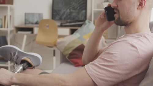 Man with Prosthetic Leg Talking on Cellphone Indoors