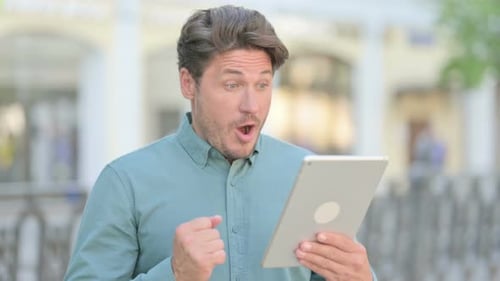 Man Celebrating Success While Using a Tablet Outdoors