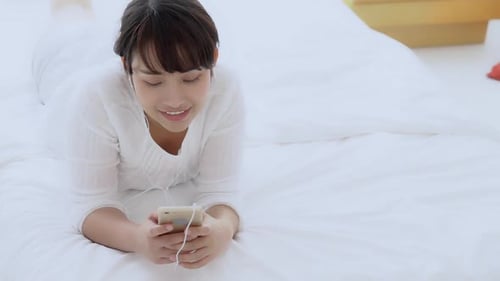 Woman Lying on Bed Using Smart Phone