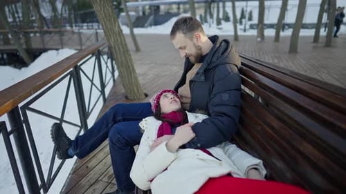Young Couple Cuddling on Bench in Winter Park