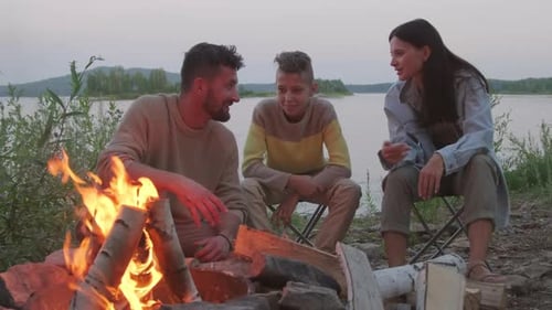 Family Chatting by Bonfire on Lake