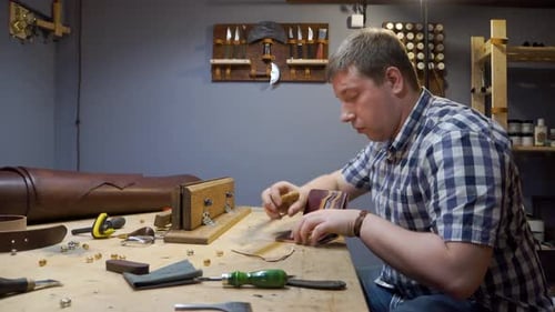 Un tailleur dans une chemise à carreaux crée un sac à main en cuir pour un design personnalisé en atelier